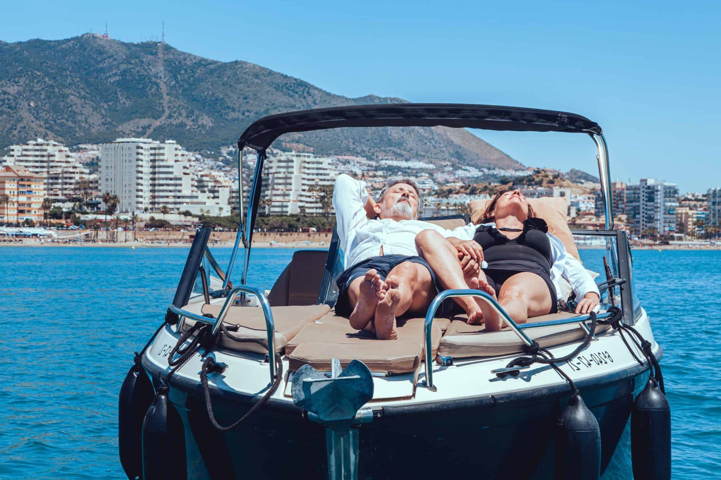 Dos personas tumbadas en la proa del Nassau III frente a Benalmádena